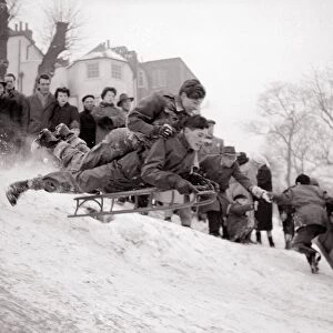 Boys goes flying down a snow covered hill on a sledge at Hampstead Heath February
