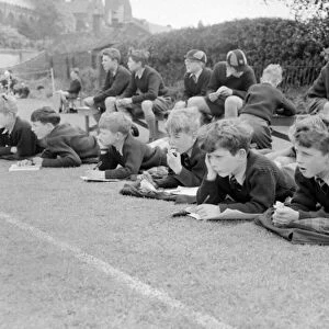 Boys lying on the grass watching a game of cricket at St Chads Cathedral School