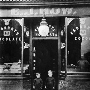 Two boys standing outside the bakery E J How, in Mill Road, Cambridge, Cambridgeshire