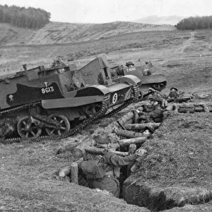 Bren gun carriers passing over a trench in which troops are taking cover during an army