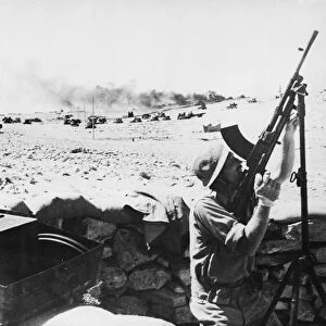 Bren gunner in action against bombers, in the background a lorry can be seen burning in