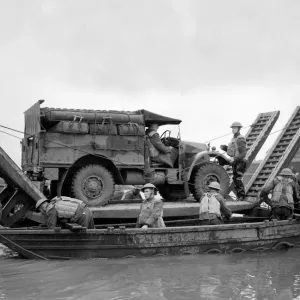 British army soldiers with an all terrain vehicle crossing over water on a pontoon during