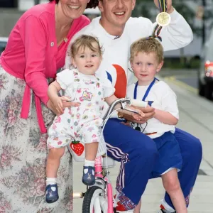 British cyclist Chris Boardman poses with his family on arrival at Manchester airport as