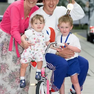 British cyclist Chris Boardman poses with his family on arrival at Manchester airport as