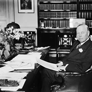British Home Secretary Sir William Joynson-Hicks sitting at his desk in his office