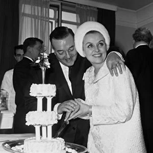 British musician Ronnie Ronalde cuts the cake with his new bride Yana after their wedding