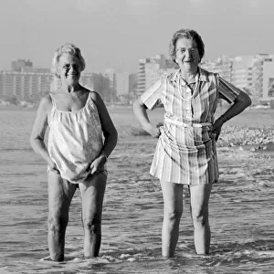 Three British pensioners enjoying their SAGA holiday, paddling in the sea on a beach in