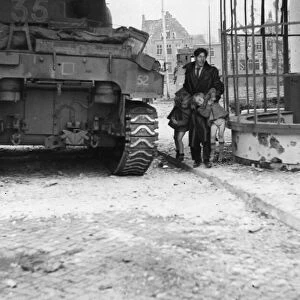 A British Sherman tank pauses for a moment as a Dutch civilian lifts his two children