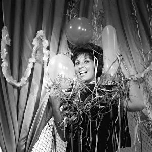 British singer Alma Cogan wraps herself in Christmas decorations at ATV House in Marble