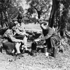 A British soldier enjoys a cup of tea with two women of the American Women