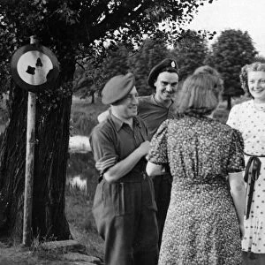 Two British soldiers chat to German women by a river bridge. June 1945