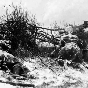 British soldiers firing a machine gun from behind a hedge in the snow