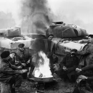 British soldiers of a tank recovery unit keep warm around a fire in the wintry weather