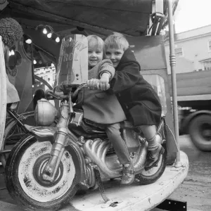 Brother and sister riding a motorcycle on a childs roundabout at the Northallerton