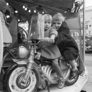 Brother and sister riding a motorcycle on a childs roundabout at the Northallerton