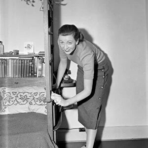 A busy housewife polishing the furniture at home Circa 1954