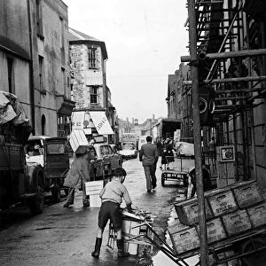 A busy street scene as traders, workmen and children go about their business