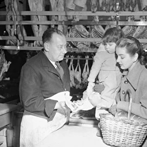 Butcher offers choice cuts of meat to a woman shopper March 1952