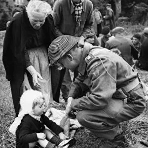 Canadian soldiers tend to French Refugees in Normandy shortly after the successful