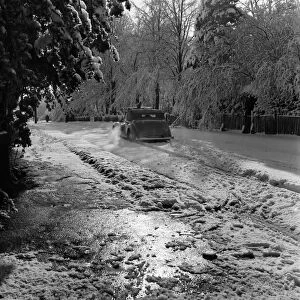 Car drives along a road covered in deep snow in Tadworth. April 1950 O23770-007