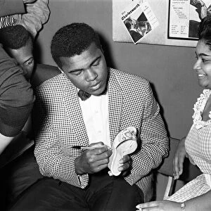 Cassius Clay aka (Muhammad Ali) signs his autograph on a slipper for a fan in London