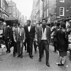 Cassius Clay (centre) et son entourage marchant à travers le marché de Berwick en route vers sa conférence de presse. Cassius Clay (centre) et son entourage marchant à travers le marché de Berwick en route vers sa conférence de presse.