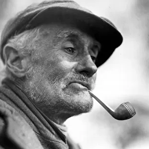 Character Studies. Old man smoking pipe wearing coth cap. P044413 Circa 1933