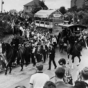 Cheering crowds greet the Denby Dale Pie, escorted by two mounted police