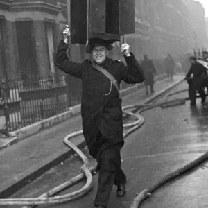A cheery policeman with a cabinet balance on his head helps salvage furniture following a