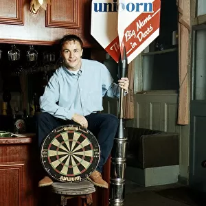 Chelsea and England footballer Dennis Wise poses in a public house with a dartboard