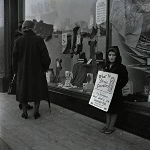 Child standing outside a shop with a poster advertising a religious meeting at