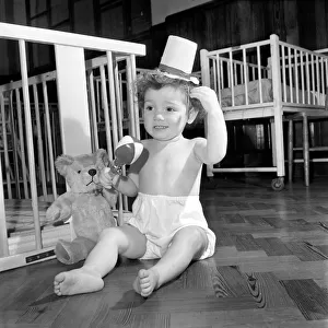 Child with teddy bear and toy top hat. December 1953 D7586-002