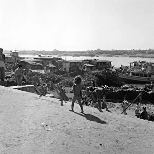 A child watches the boats unloaded in Dacca, Bangladesh. February 1961 l