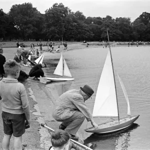 Children and adults sailing their toy yachts on the Round Pond in Kensington Gardens Children and adults sailing their toy yachts on the Round Pond in Kensington Gardens
