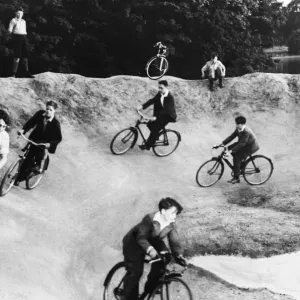 Children cycling around a crater on a bomb site during Second World War. Circa 1944