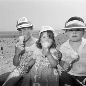 Children enjoy an ice cream as they try to keep cool on Coney Beach in Porthcawl Children enjoy an ice cream as they try to keep cool on Coney Beach in Porthcawl