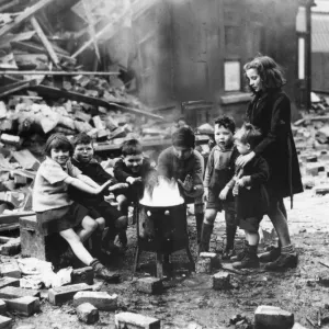 Children in a Manchester suburb warm themselves by a fire outside wrecked houses during Children in a Manchester suburb warm themselves by a fire outside wrecked houses during