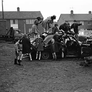 Children play on the wreck of a dumped car at Kirkby, Liverpool. 18th March 1965