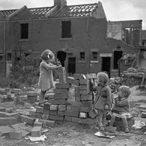 Children playing games on a bomb site in London, three little girls play with bricks