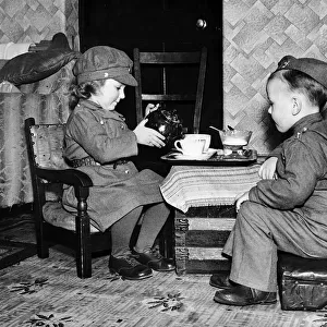 Children playing games at home dressed in army uniform and pouring tea during WW2