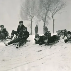 Children sledging down a hill in snow smiling and laughing after a havy snowfall