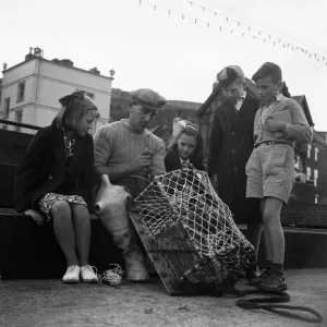 Children watching a fisherman at work with his net. North Yorkshire coast Children watching a fisherman at work with his net. North Yorkshire coast
