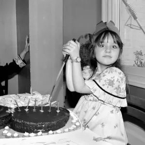 Childrens birthday party: The birthday girl cuts the cake. March 1981 PM 81-01186b-001 Childrens birthday party: The birthday girl cuts the cake. March 1981 PM 81-01186b-001