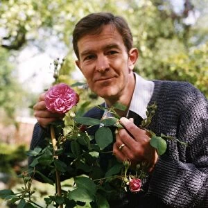 Christopher Ravenscroft Actor holding rose bush flower in garden