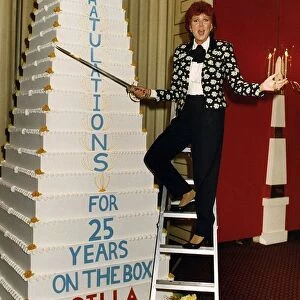 Cilla Black on a step ladder about to cut her cake with a sword celebrating her 25