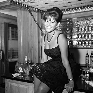 Claudia Cardinale actress sitting on bar February 1962