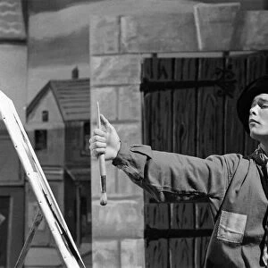 Cliff Richard on the set of the film Summer Holiday, painting with a brush and easel