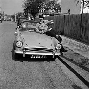Cliff Richard sitting on a car. He has just bought a new house in Winchmore Hill