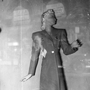 Clothing - A manikin in shop window displaying a coat for sale. Spring fashions