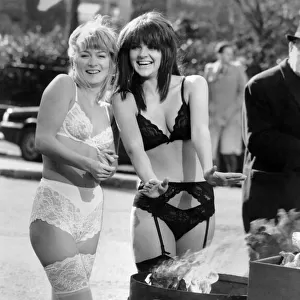 Clothing Underwear: Chilly models in lingerie warm up from a fire in a bin in the street